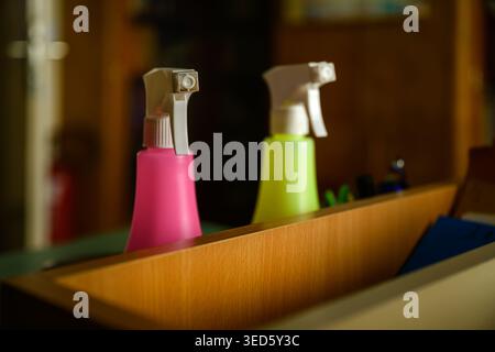 Pink and lime spray bottles in wooden drawer, close-up with selective focus Stock Photo