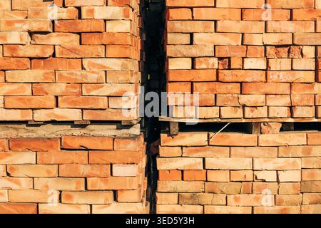 Architectural texture of neatly stacked red clay bricks in tall pallets, divided by a dramatic vertical shadow gap in the center, selective focus Stock Photo