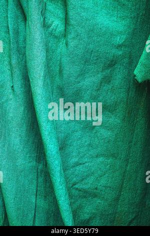 Close-up green textured fabric with folds and wrinkles, vertical image Stock Photo
