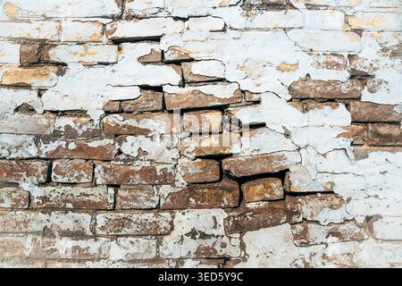 Texture of old damaged cracked weathered brick wall, thick layers of white paint are cracking, flaking and peeling of as background Stock Photo