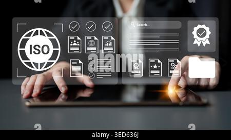 A professional workspace featuring hands interacting with a tablet displaying ISO documents and checklists, symbolizing quality management and Stock Photo