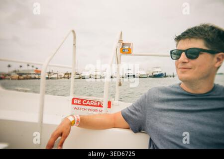 Man wearing sunglasses traveling by boat in marina Stock Photo