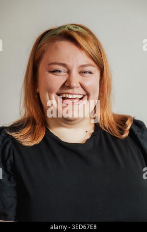 Close-up of woman with big smile, auburn hair, neutral background Stock Photo