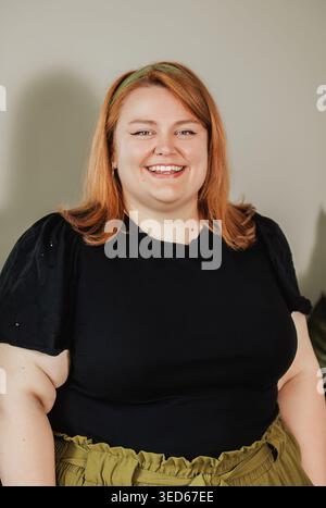 Woman with bright smile, black eyelet top, neutral background Stock Photo