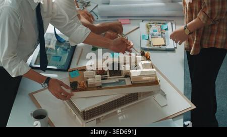 Smart architect or civil engineer writing building structure idea on note and stick on blueprint. Aerial view of manager working together with diverse Stock Photo
