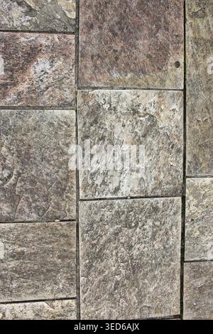 High-angle full-frame shot of an outdoor stone floor pattern. The textured pavement features various earth tones including grey, brown, and reddish hu Stock Photo
