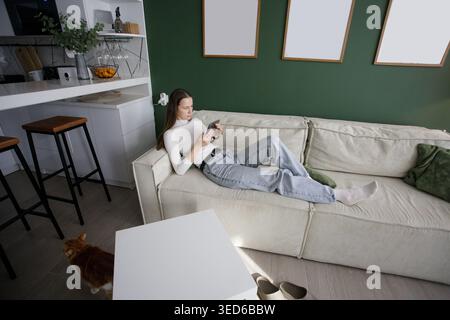 woman using digital reader electronic book at home. Beautiful model with long hair in white and green interior indoor Stock Photo
