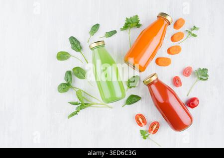 Fresh tomato, carrot, spinach juices in glass bottles with ingredients on white wood board, mock up for design, advertising, branding identity product. Stock Photo