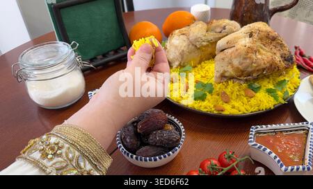 Woman eating Kabsa with her hands. Saudi Arabia Kabsa rice with roasted chicken served on Iftar table Stock Photo