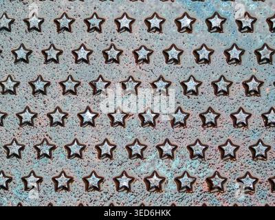 Weathered metal sheet with star-shaped embossed relief, rusty patina texture close-up for grunge backgrounds Stock Photo