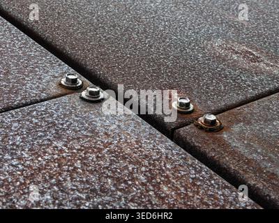 Angled close-up of weathered Corten steel seam with hex bolts, industrial texture detail Stock Photo