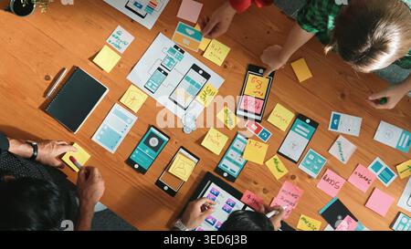 Top view of software developer team looking Ux Ui design for mobile phone interface from tablet while comparing and planning wireframe prototype Stock Photo