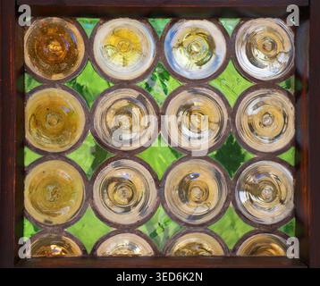 Abstract vintage tainted glass block window with circular patterns and green background. Close-up traditional texture of decorative glass panel frame. Stock Photo