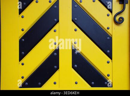 Closeup of a yellow and black chevron pattern with industrial metal texture and rivets. Abstract geometric background, diagonal striped design. Stock Photo