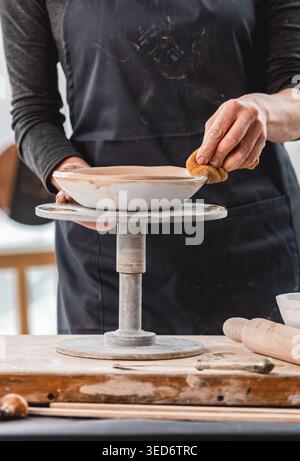 Close-Up Of Woman's Hands Making Clay Plate In Ceramics Workshop Stock Photo