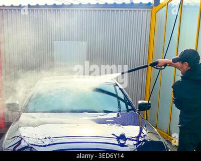 A man washes a car at a self-service car wash. Car wash concept Stock Photo