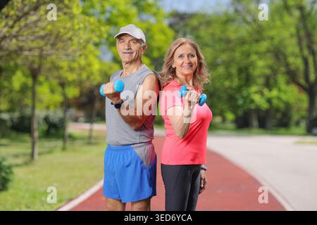 Senior couple exercising with dumbbells in a park Stock Photo