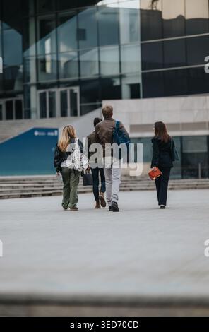 Students walking together on a university campus with backpacks and learning outdoors Stock Photo