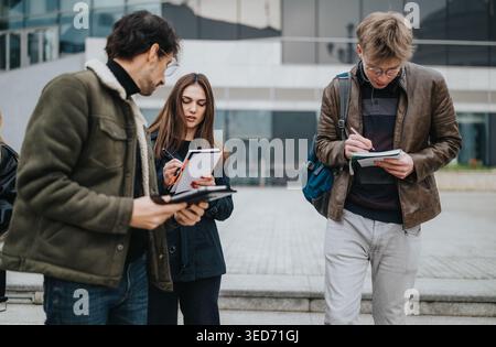 High school students studying together outdoors taking notes on campus steps in casual clothing Stock Photo