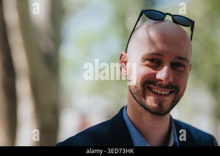 Smiling bald businessman portrait outdoors wearing sunglasses on head and blazer Stock Photo