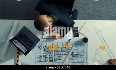 Architect engineer working while working on laptop with sticky notes and calculator to design building construction. Smart manager working and using Stock Photo