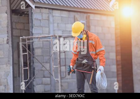 Male construction worker wearing a fae mask standing on scaffolding at a construction site Stock Photo