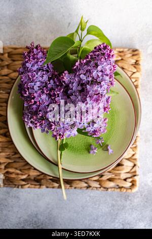 Overhead view of a rustic Spring place setting on a table with purple lilac flowers Stock Photo