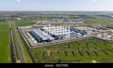 Aerial view of Datacenter Westpoort featuring large industrial cooling units and surrounding green fields with a railway track in Groningen, Groningen Stock Photo