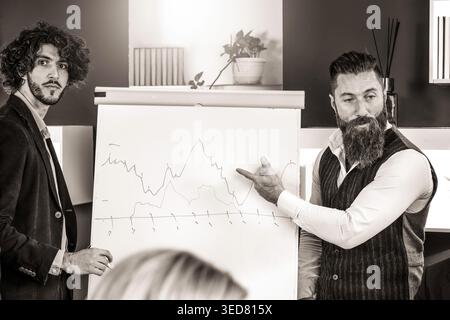 Business presentation with financial chart during corporate meeting in modern office. Millennials and generation x professionals analyzing market tren Stock Photo