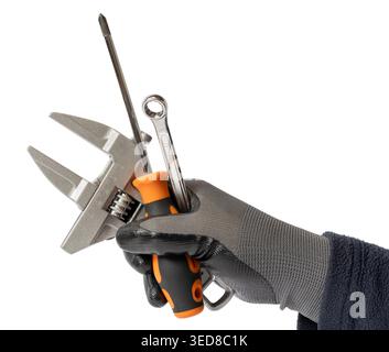 Gloved hand holding a group of tools like an adjustable wrench, screwdriver, and spanner isolated on white background Stock Photo
