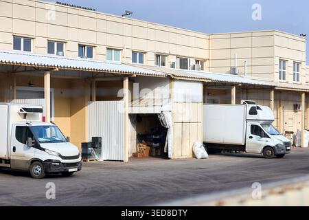 Distribution center with loading bays shipping containers forklift and transport vehicles. White commercial delivery van parked alongside wooden palle Stock Photo