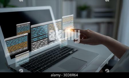 A hand interacting with floating digital data displays above a laptop, symbolizing modern technology and innovative programming in a sleek workspace Stock Photo