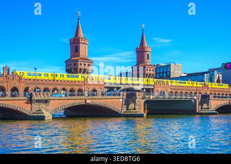 A yellow subway train crosses the historic Oberbaum Bridge over the Spree River in the Berlin cityscape. Stock Photo