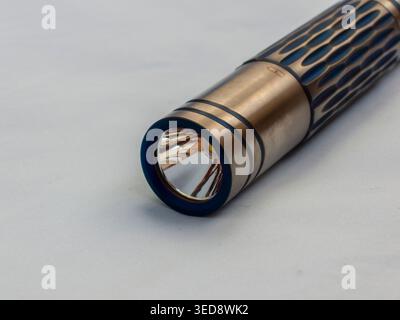Custom titanium flashlight on sky blue background Stock Photo