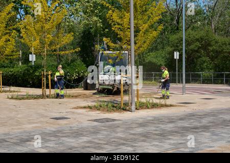 Viladecans, Spain - May 04, 2026: Maintenance crew performing urban cleaning tasks in a park area with young trees, using professional machinery to Stock Photo