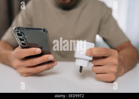 Male hand connecting smart plug to home automation system using smartphone app, managing smart devices and establishing internet of things connection Stock Photo
