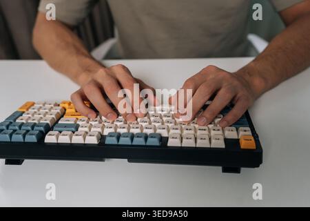 Close-up of person hands typing on stylish wireless mechanical keyboard with colored keycaps, demonstrating efficient digital work, productivity and Stock Photo