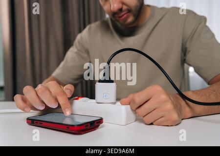 Cropped shot man controlling smart socket device connected to power strip using mobile phone application for home automation, managing energy Stock Photo