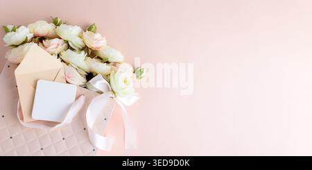 Festive composition featuring a quilted pink gift bag filled with cream and blush artificial rose flowers, accented by a white ribbon bow and gift car Stock Photo