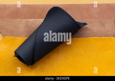 Black Rolled Leather Hide on Colorful Leather Sheets Yellow and Brown Background Stock Photo