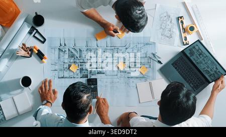 Top down aerial view of interior designer writing at sticky note while planning design with engineer team. Group of diverse architect and skilled Stock Photo