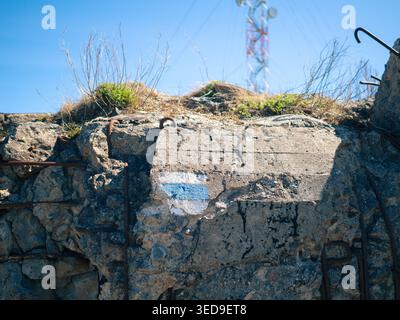 Blue and white trail marker painted on limestone cliff face with rusted iron hooks at Paldiski, Estonia Stock Photo