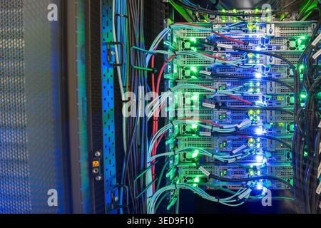 Explore a detailed view of a modern server room featuring illuminated servers, colorful cables, and advanced technology vital for data management and Stock Photo