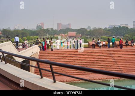 Visitors gather at the Lotus Temple (Bahá'í House of Worship) in New Delhi, India. The scene shows wide red sandstone steps leading to a water Stock Photo