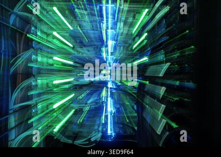A vibrant light display emerges from a data server, showcasing blue and green lights amidst a blur of motion. This abstract image illustrates the ener Stock Photo