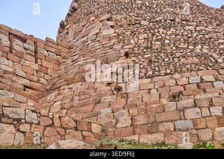 Ancient stone fortification wall constructed from weathered reddish-brown and beige masonry blocks, featuring rough textured surfaces and visible Stock Photo