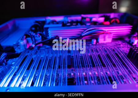 Close-up view of a technology circuit featuring vibrant neon lights. The intricate arrangement of wires and components showcases modern electronics an Stock Photo