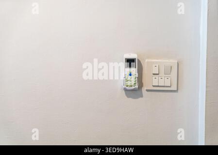This image features a modern wall-mounted security alarm system and a control switch panel, representing smart home security and household safety tech Stock Photo