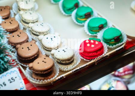 A vibrant display of animal-shaped cookies and macarons arranged on a tray, featuring bear faces in white, brown, red, and green, perfect for festive Stock Photo