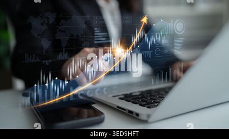 A business professional analyzes financial data on a laptop while a digital graph illustrates upward trends, highlighting the importance of data in Stock Photo